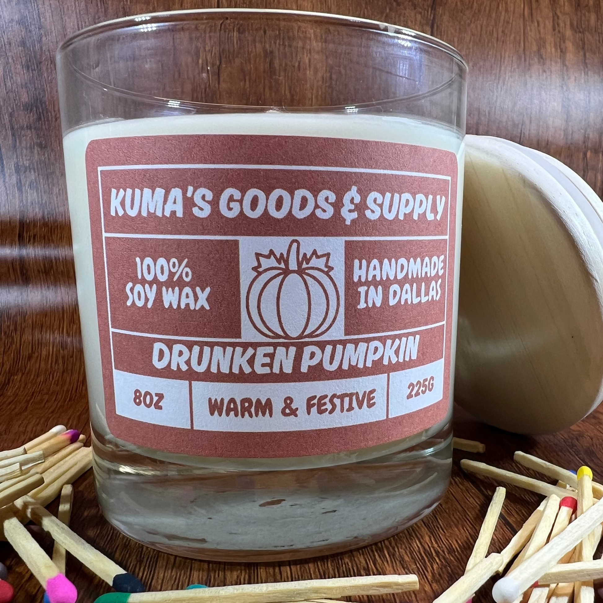 Kuma's Goods & Supply Drunken Pumpkin candle with matches on a wooden surface